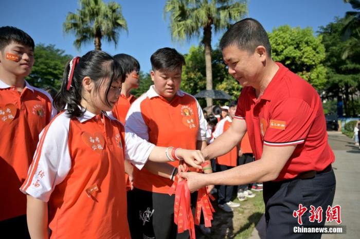 資料圖：廣西華僑實(shí)驗(yàn)高中的教師為高三學(xué)子系上紅絲帶，盼望學(xué)子高考必勝。 俞靖 攝